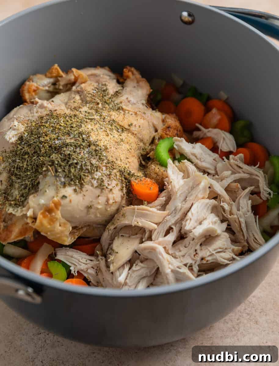 Rotisserie Chicken Noodle Soup Recipe for Quick Weeknight Meals 6 Shredded rotisserie chicken and chicken carcass in pot with carrots, celery and onion.