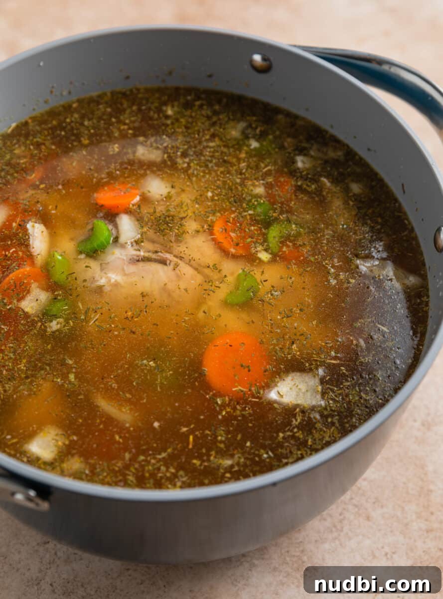 Rotisserie Chicken Noodle Soup Recipe for Quick Weeknight Meals 7 Broth poured over chicken soup ingredients in pot.