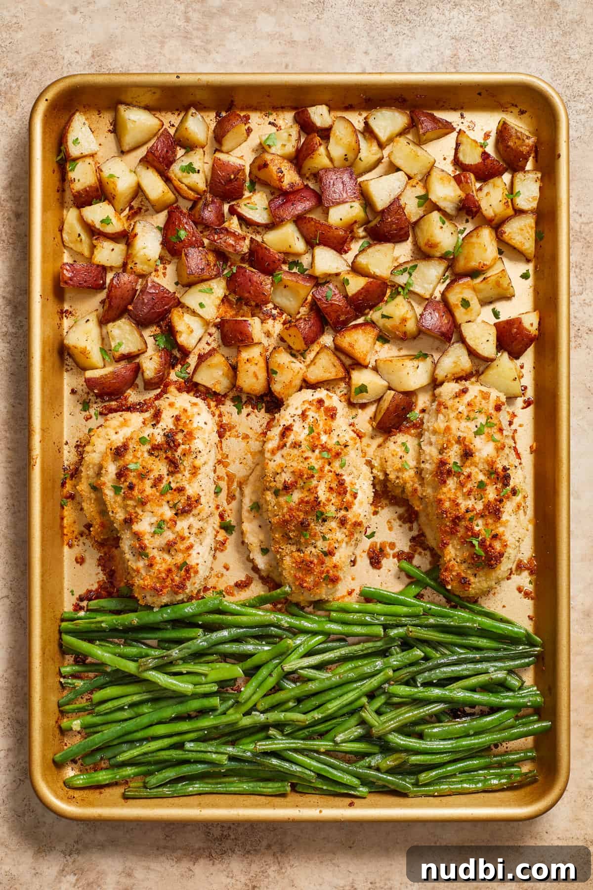 Parmesan-Crusted Chicken Sheet Pan Dinner Recipe 2 Parmesan sheet pan chicken dinner cooked with potatoes and green beans on gold pan.