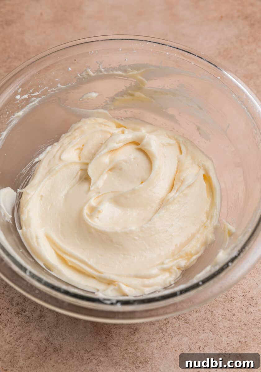 Red Velvet Cheesecake Dip Recipe — Creamy Party Dessert Dip 5 Cream cheese and sugar mixture creamed together in glass mixing bowl.