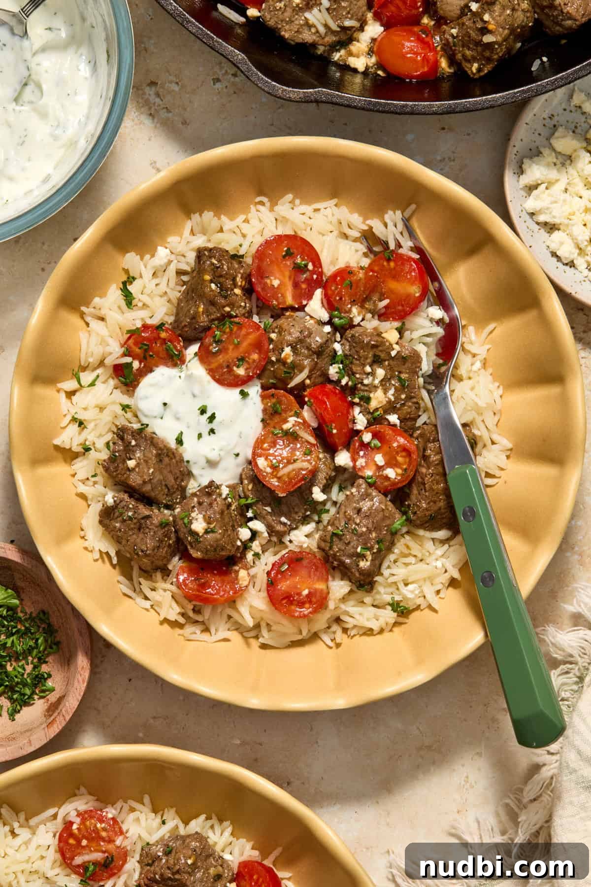 Mediterranean Steak Bites with Creamy Yogurt Herb Sauce 4 Bowl with rice and steak bites with yogurt dill sauce.