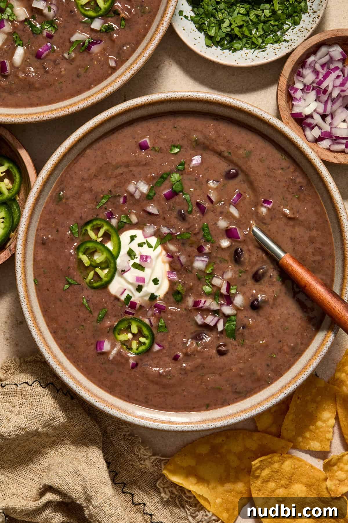 20-Minute Hearty Black Bean Soup Recipe for Weeknight Dinners 2 Bowl of black bean soup topped with cilantro, onions and sour cream.