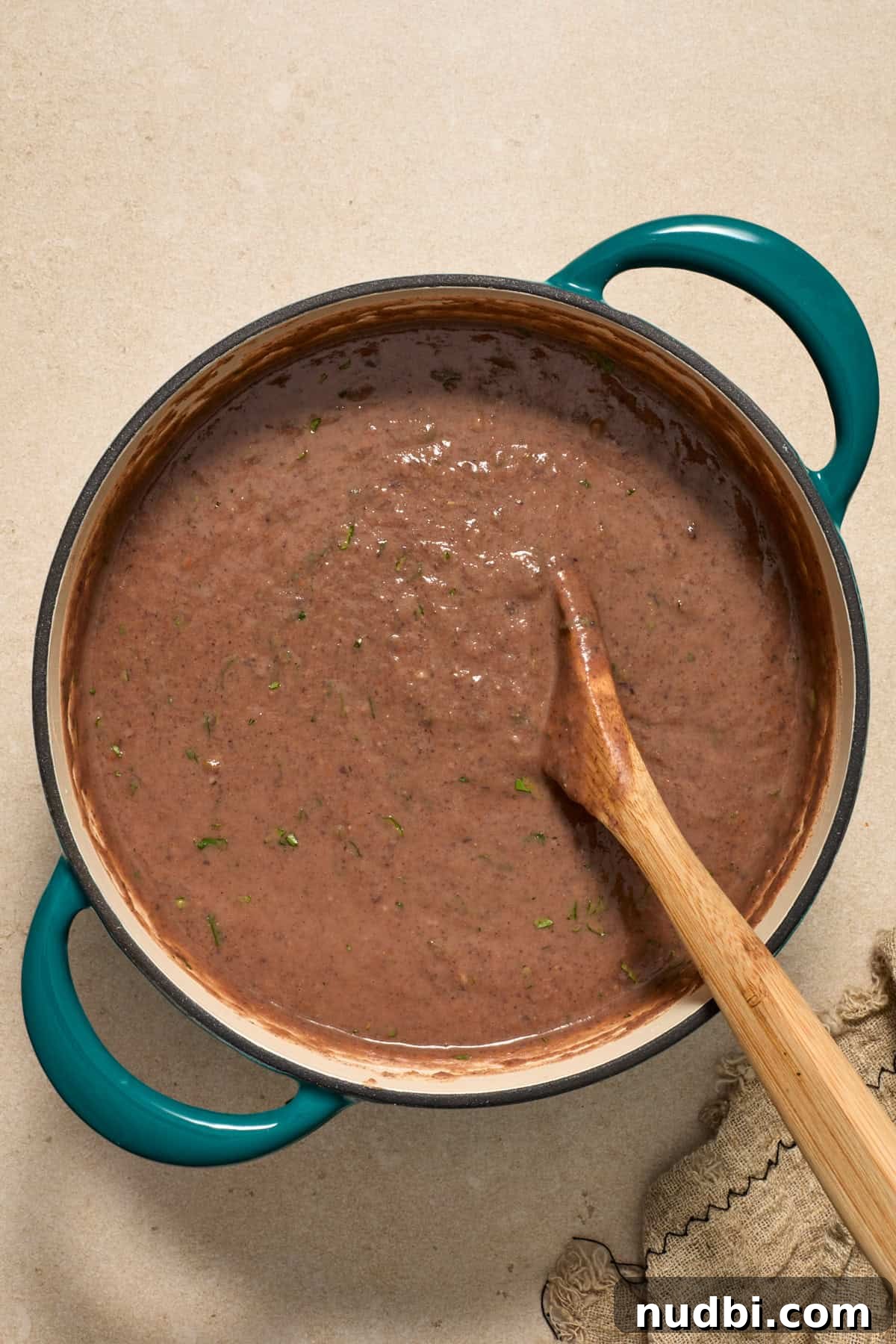 20-Minute Hearty Black Bean Soup Recipe for Weeknight Dinners 9 Black bean soup prepped in pot with spoon stirring into the mixture.