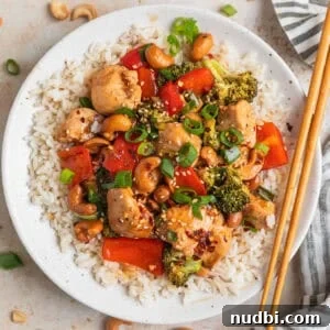 Crispy Baked Cashew Chicken with Garlic Soy Glaze 11 Baked cashew chicken over rice on plate with chopsticks.