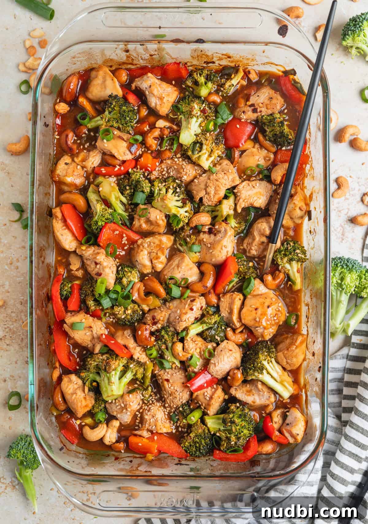Crispy Baked Cashew Chicken with Garlic Soy Glaze 3 Baking pan with easy cashew chicken recipe in sauce and topped with sesame seeds and sliced scallions.