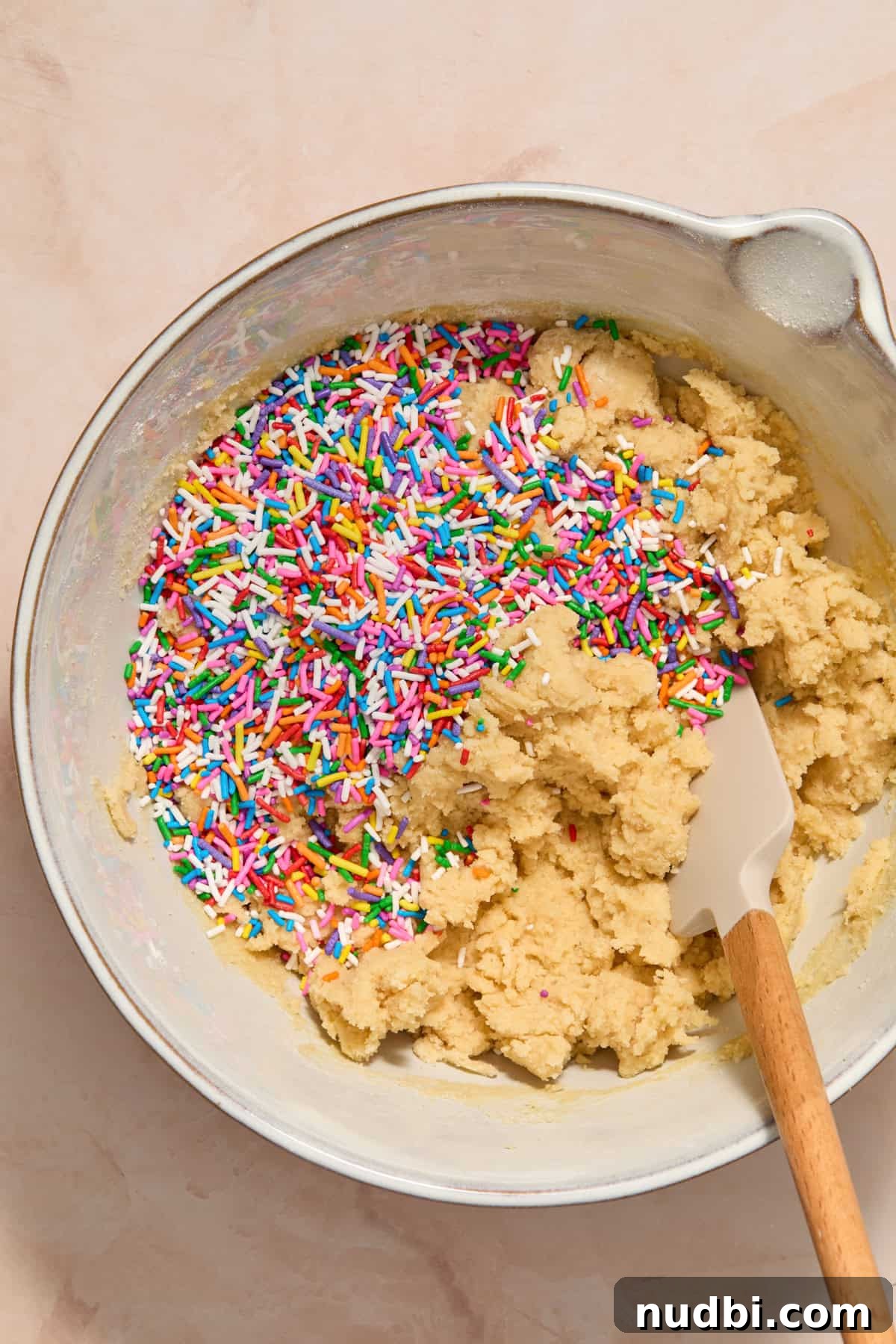Funfetti Birthday Cake Cookies Recipe for Colorful Party Treats 8 Rainbow sprinkles poured into bowl with birthday cake cookie dough mixture.