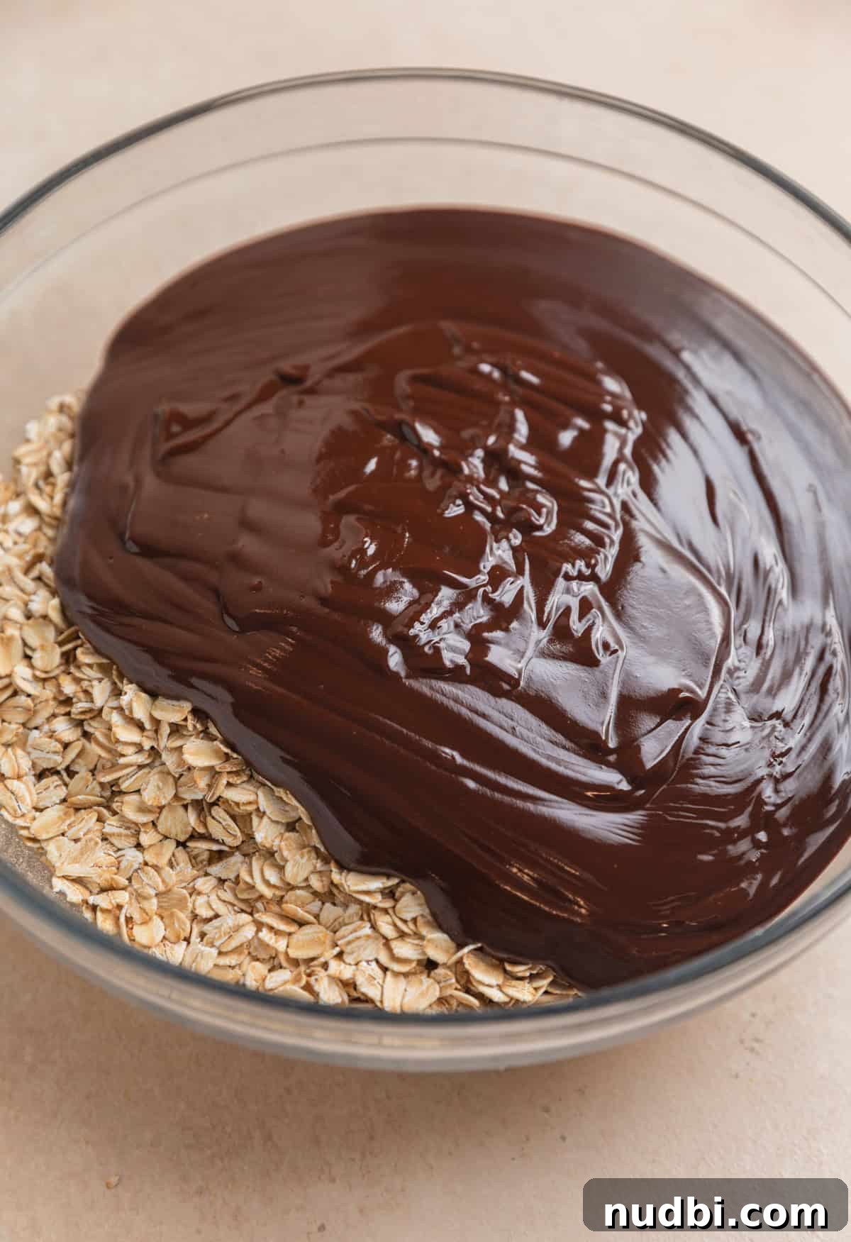 No-Bake Peanut Butter Chocolate Oatmeal Bars Recipe 5 Melted chocolate mixture poured over rolled oats in glass bowl.