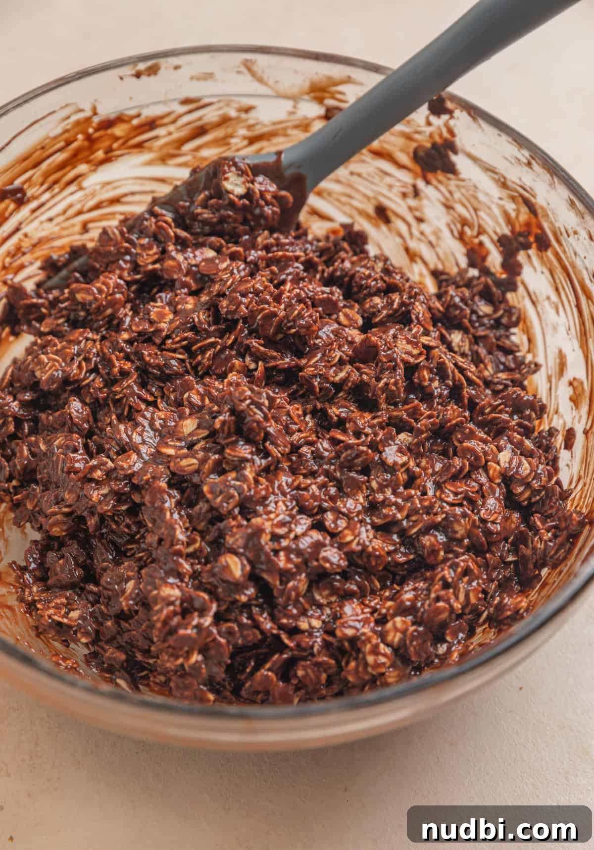No-Bake Peanut Butter Chocolate Oatmeal Bars Recipe 6 Peanut butter chocolate and oatmeal mixture with spatula in glass bowl.
