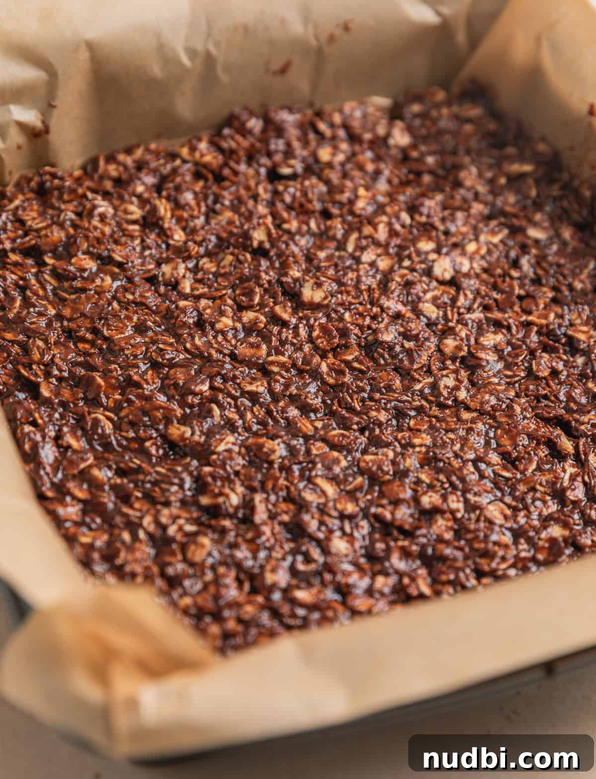 No-Bake Peanut Butter Chocolate Oatmeal Bars Recipe 7 No bake peanut butter oat bars in square pan lined with parchment.