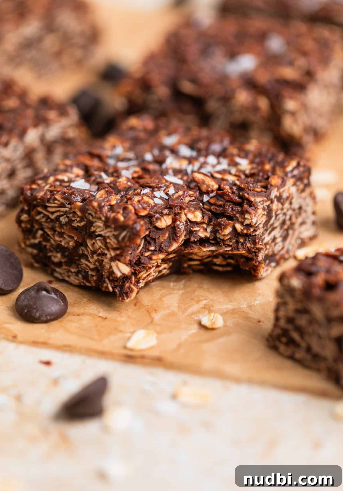 No-Bake Peanut Butter Chocolate Oatmeal Bars Recipe 9 Peanut butter chocolate oatmeal bar with bite taken out of it laying on parchment.