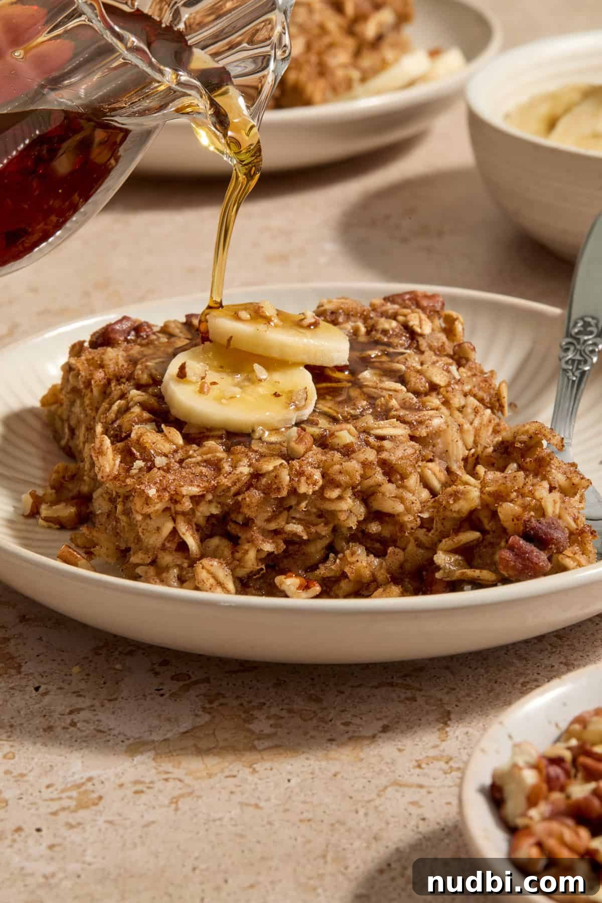 Banana Bread Baked Oatmeal Recipe for Breakfast and Meal Prep 2 Banana bread baked oatmeal on plate with maple syrup poured over top.