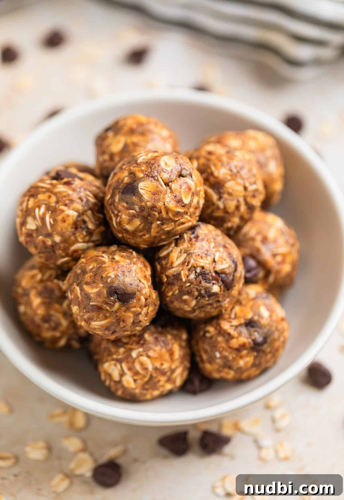 No-Bake Peanut Butter Oatmeal Energy Balls for Quick Snacks 2 White dish with no bake oatmeal peanut butter balls with rolled oats and chocolate chips surrounding.