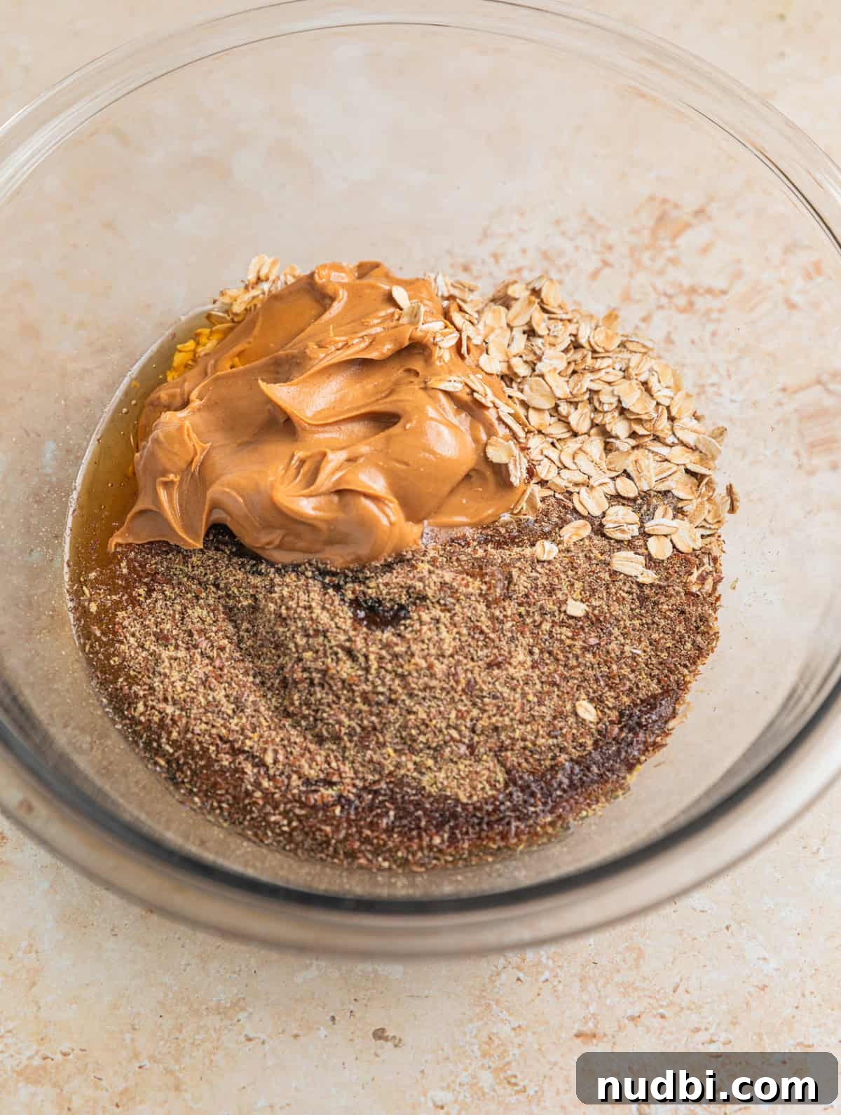 No-Bake Peanut Butter Oatmeal Energy Balls for Quick Snacks 4 Peanut butter, oats, flax, maple and honey in glass mixing bowl.
