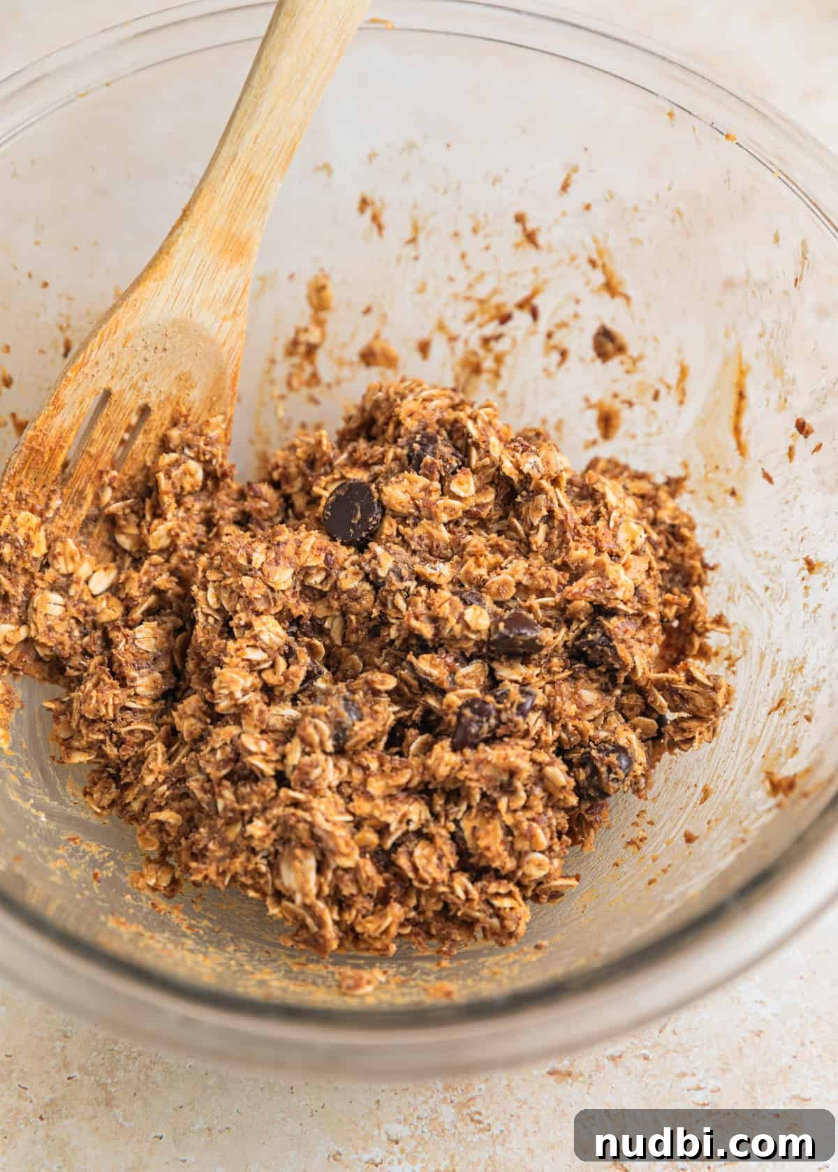 No-Bake Peanut Butter Oatmeal Energy Balls for Quick Snacks 6 Chocolate chips stirred into oat mixture in glass bowl with wooden spoon.
