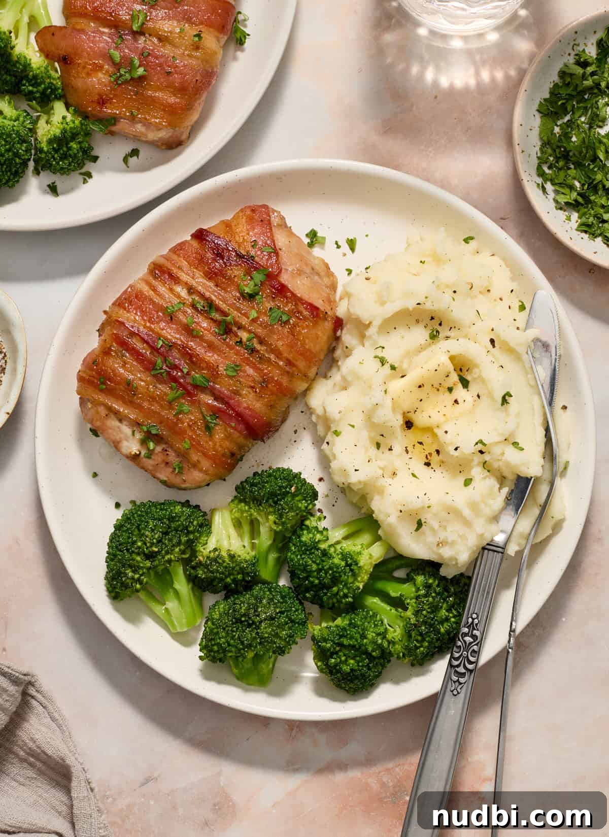 Maple-Glazed Bacon-Wrapped Pork Chops with Crispy Edges 2 Overhead view of plate with bacon wrapped pork chop, broccoli and mashed potatoes.