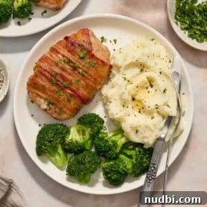 Maple-Glazed Bacon-Wrapped Pork Chops with Crispy Edges 11 White plate with pork chop dinner including mashed potatoes and broccoli.