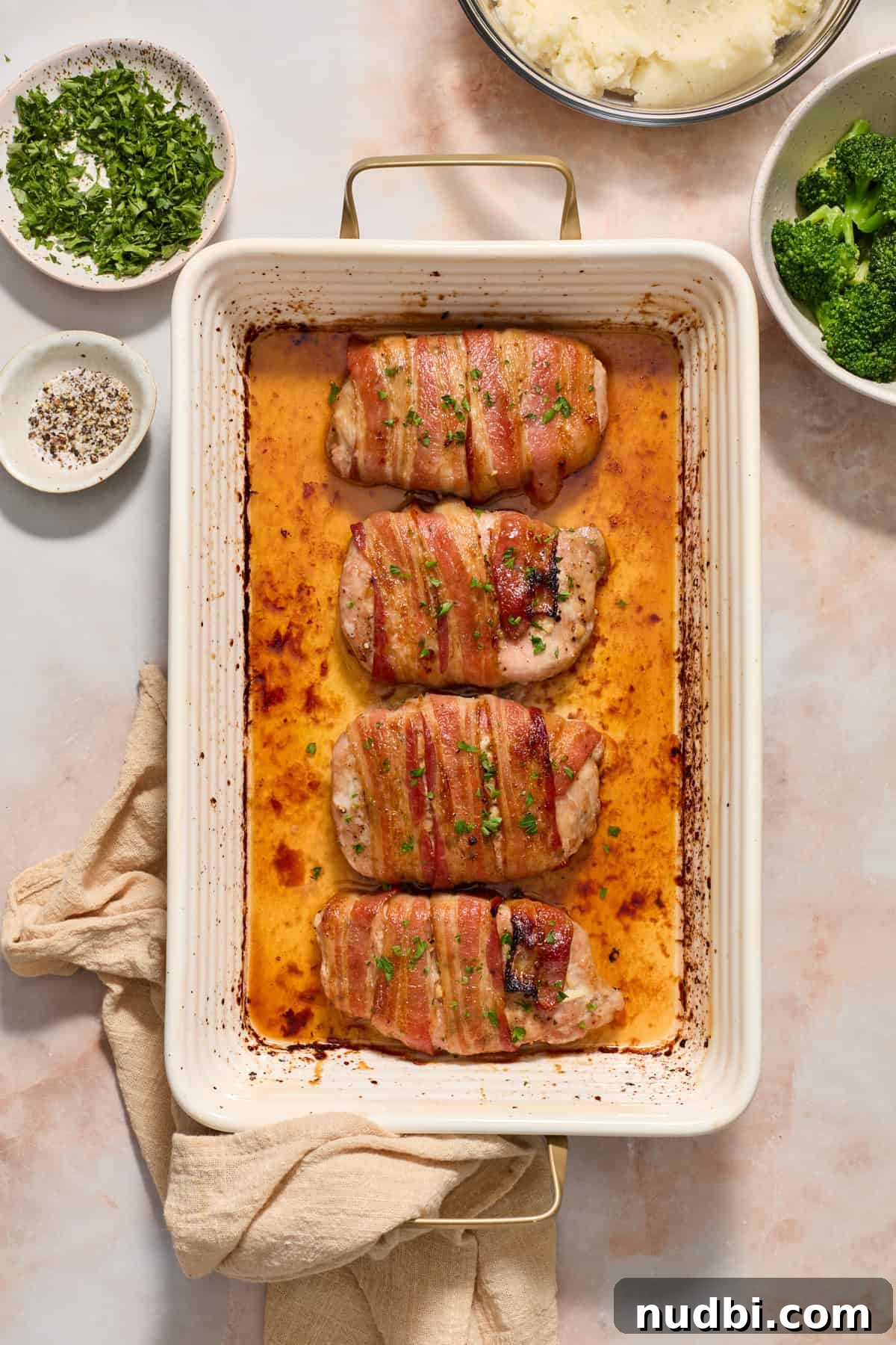 Maple-Glazed Bacon-Wrapped Pork Chops with Crispy Edges 3 Maple bacon wrapped pork chops in baking pan topped with parsley.