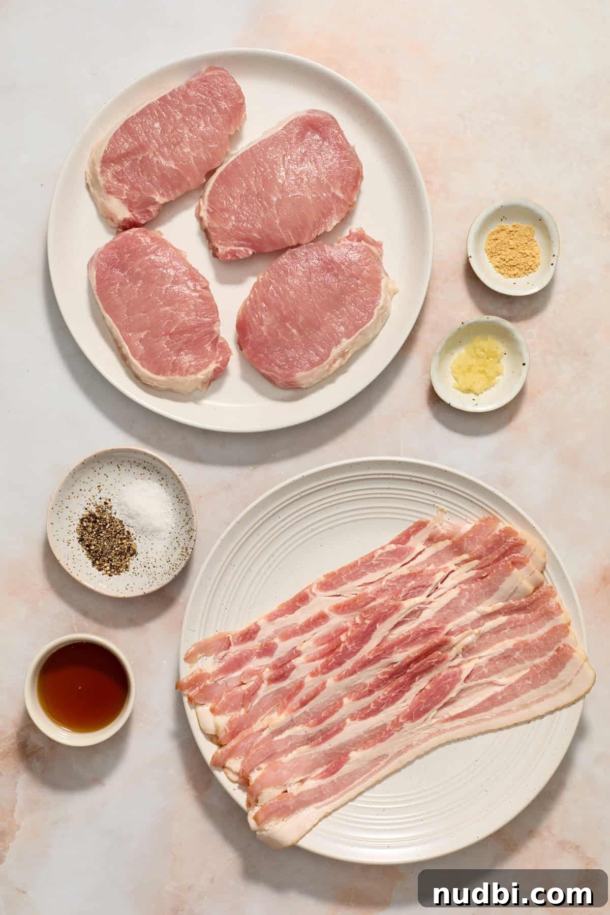 Maple-Glazed Bacon-Wrapped Pork Chops with Crispy Edges 4 Pork chops, bacon, syrup and other ingredients arranged on surface.