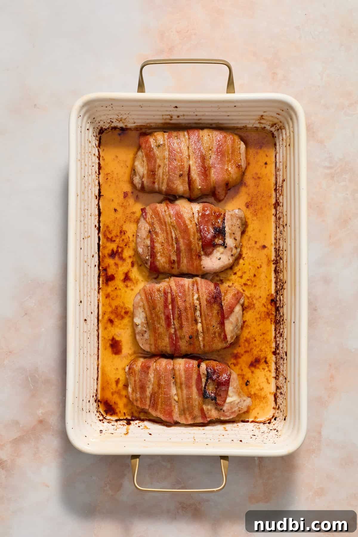 Maple-Glazed Bacon-Wrapped Pork Chops with Crispy Edges 8 Baked maple bacon wrapped pork chops in baking dish.