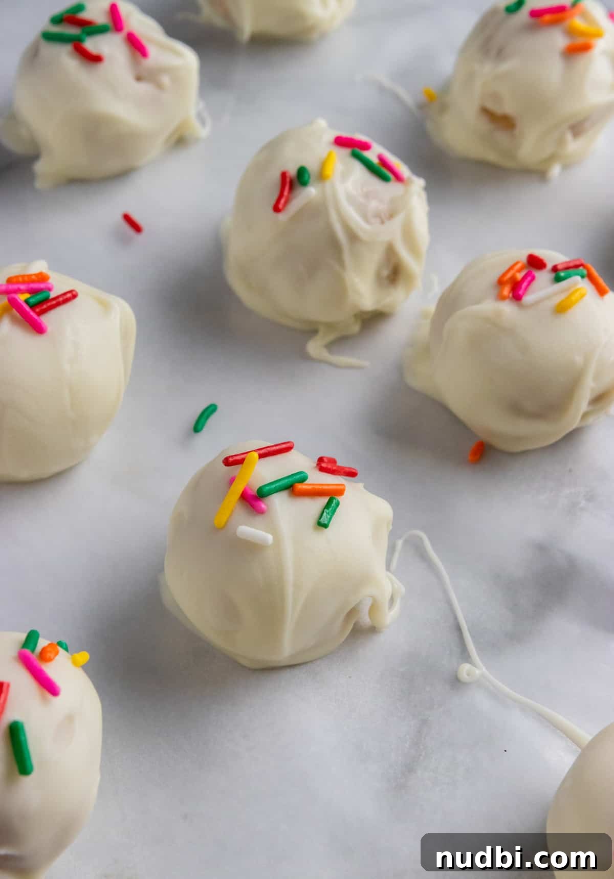 Golden Oreo Truffles Recipe — Creamy No-Bake Dessert Bite 3 Oreo Truffles on parchment paper with sprinkles.