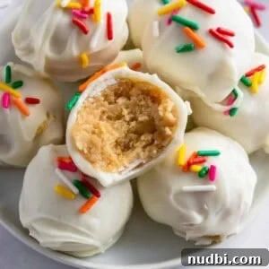 Golden Oreo Truffles Recipe — Creamy No-Bake Dessert Bite 8 Golden Oreo truffles arranged on white plate with bite taken out of one.