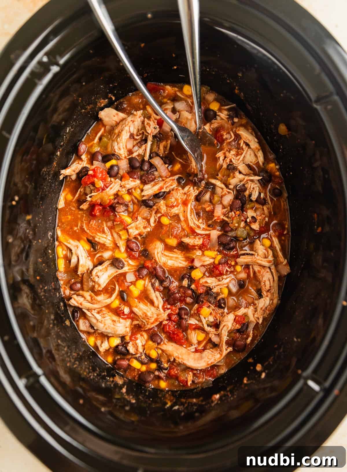 Slow Cooker Chicken Burrito Bowl: Flavorful Make-Ahead Recipe 7 Forks shredding chicken and black bean mixture in crock pot.