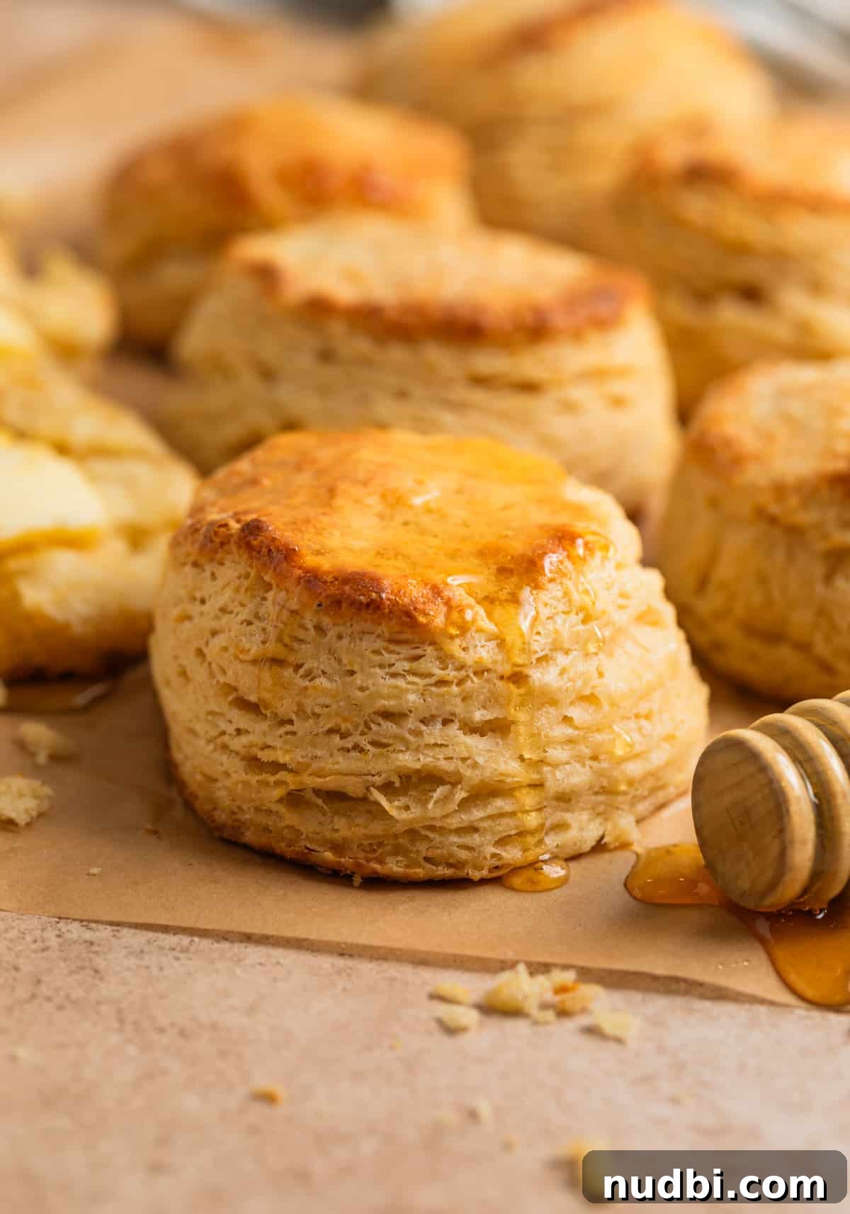 Honey Biscuits Recipe: Soft, Buttery Honey Biscuits in 30 Minutes 2 Honey biscuits lined on parchment with drizzle of honey.