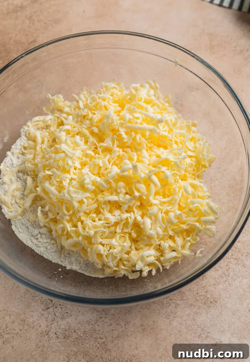 Honey Biscuits Recipe: Soft, Buttery Honey Biscuits in 30 Minutes 4 Grated butter in glass mixing bowl with flour mixture.