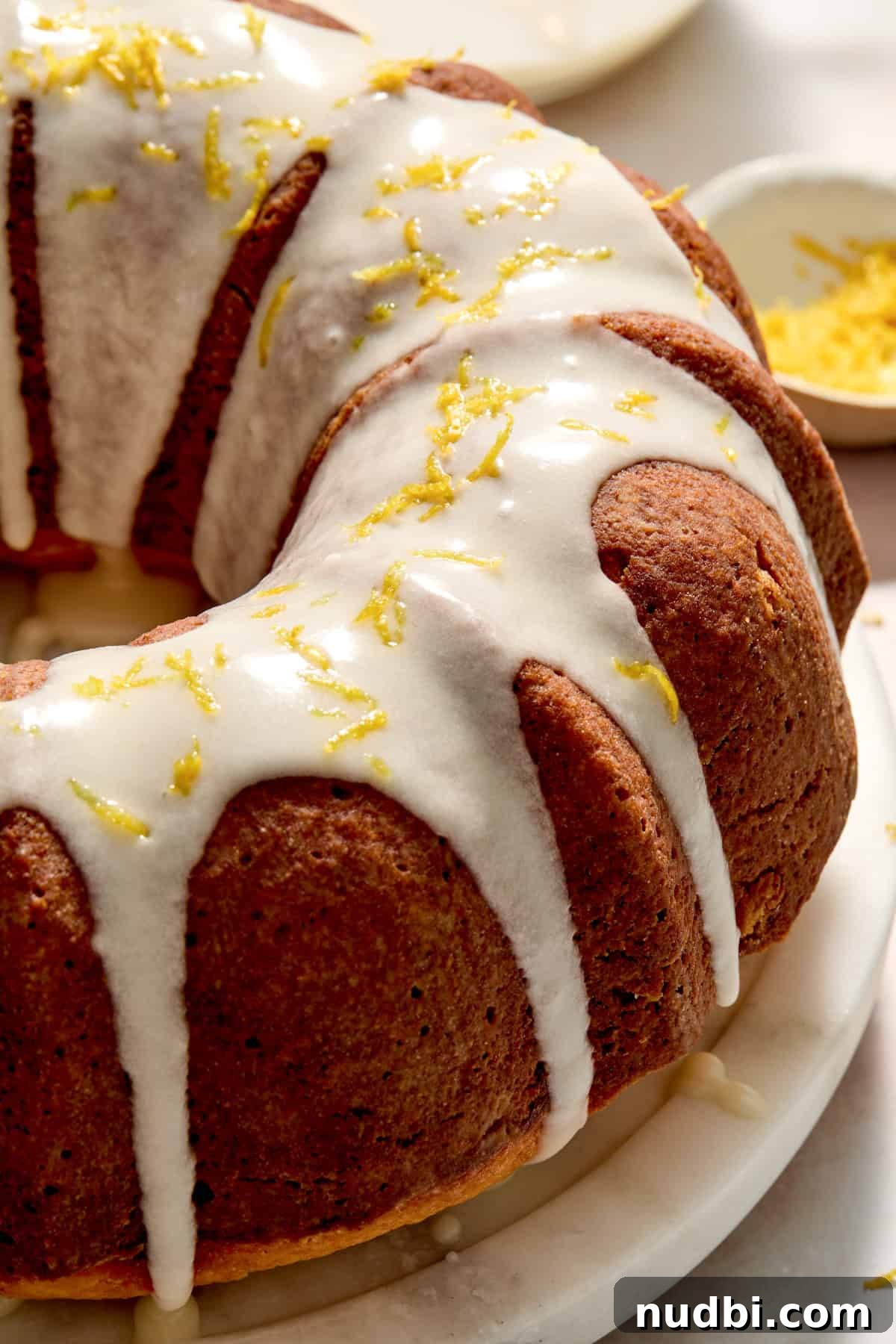 Champagne-Infused Lemon Bundt Cake Recipe 2 Champagne lemon bundt cake with lemon icing drizzled over top and lemon zest.