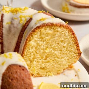 Champagne-Infused Lemon Bundt Cake Recipe 10 Lemon bundt cake on cake plate with slice cut out to show texture of cake.