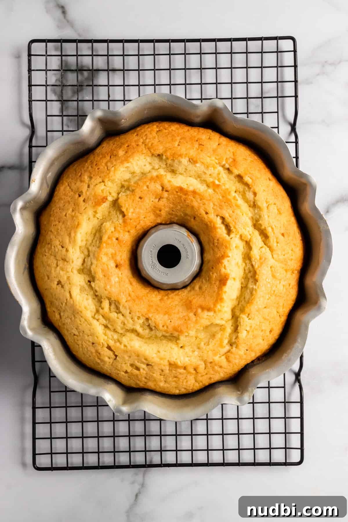 Champagne-Infused Lemon Bundt Cake Recipe 8 Freshly baked cake in pan on cooling rack.