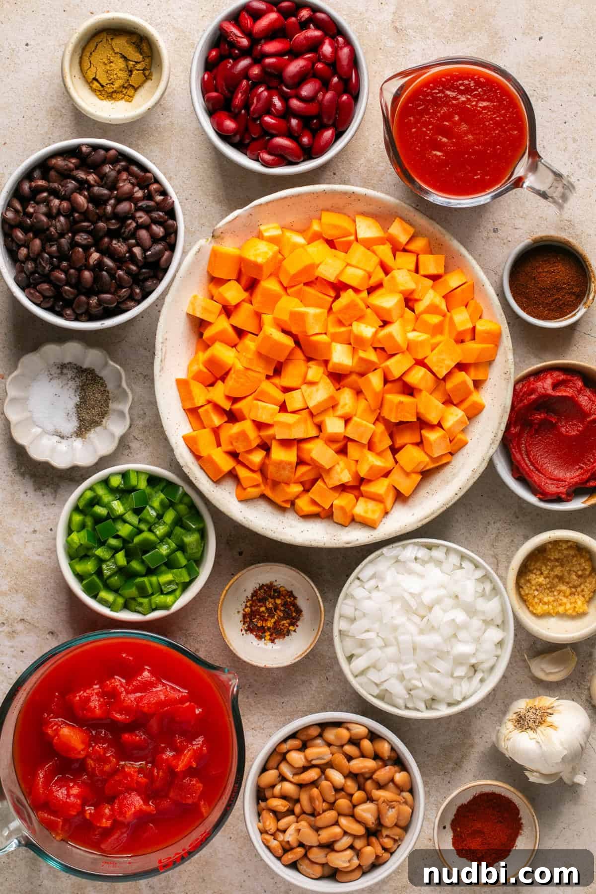 Slow Cooker Sweet Potato and Black Bean Chili Recipe 3 Sweet potatoes, beans, tomatoes, tomato sauce, spices and other ingredients arranged on surface needed to make slow cooker sweet potato chili recipe.