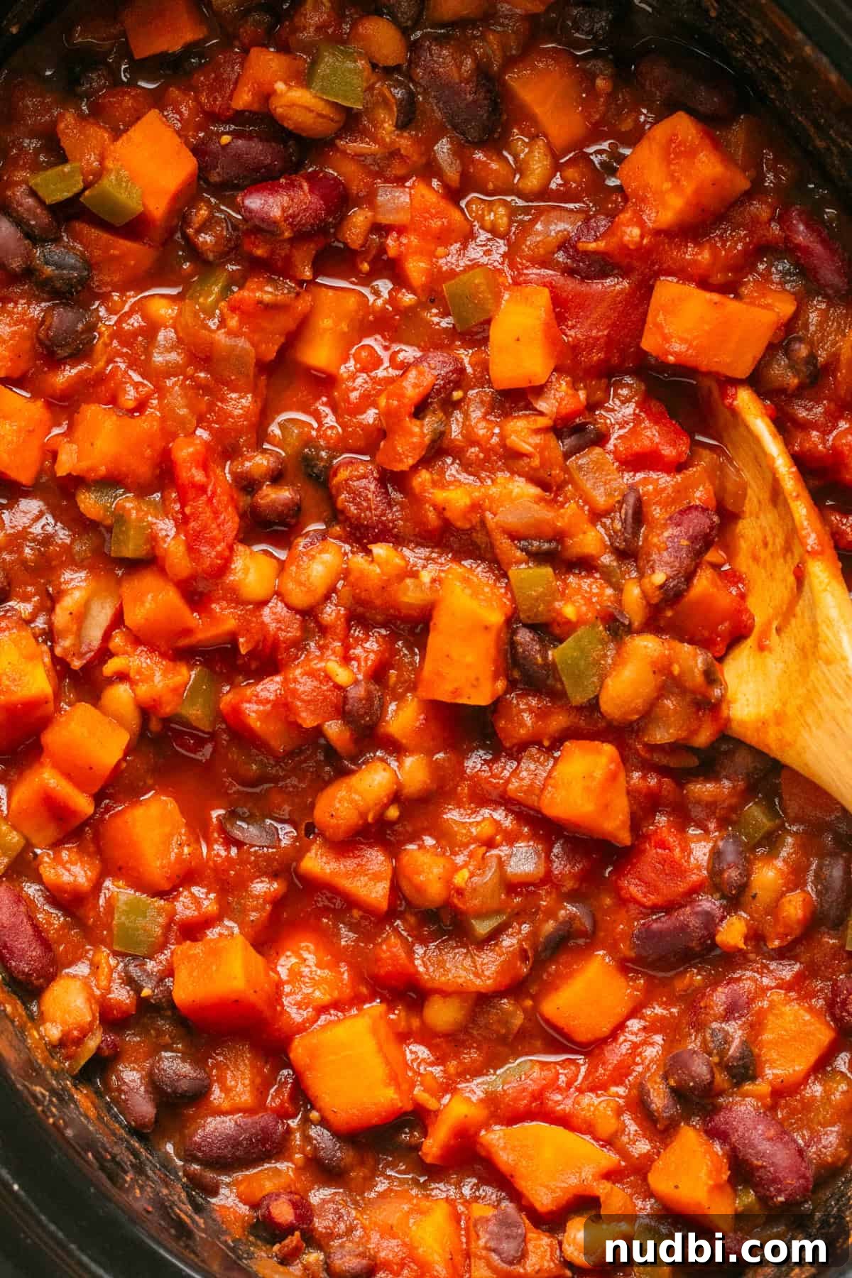Slow Cooker Sweet Potato and Black Bean Chili Recipe 8 Close up view of slow cooker sweet potato chili in crock pot with wooden spoon.