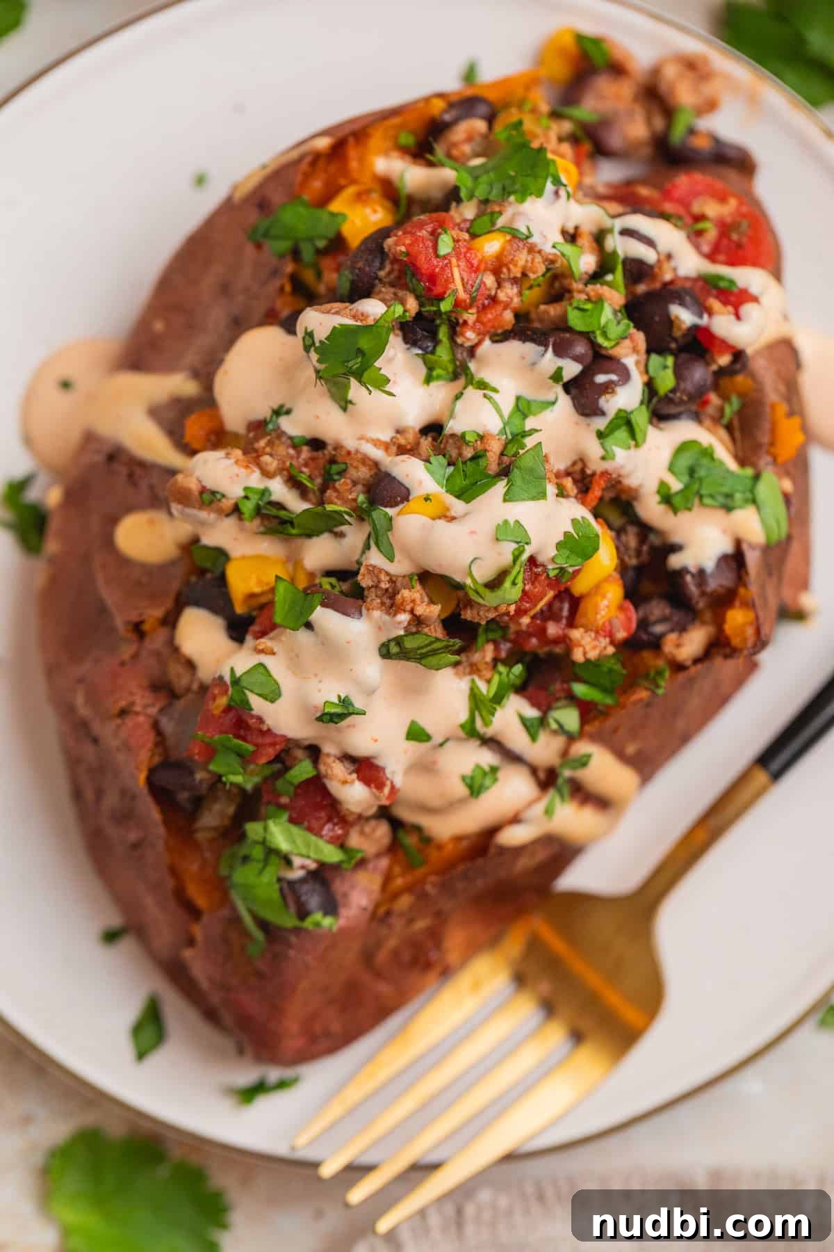 Taco-Stuffed Sweet Potatoes That Are Ready in 30 Minutes 10 Overhead view of taco stuffed sweet potato topped with cream sauce and cilantro.