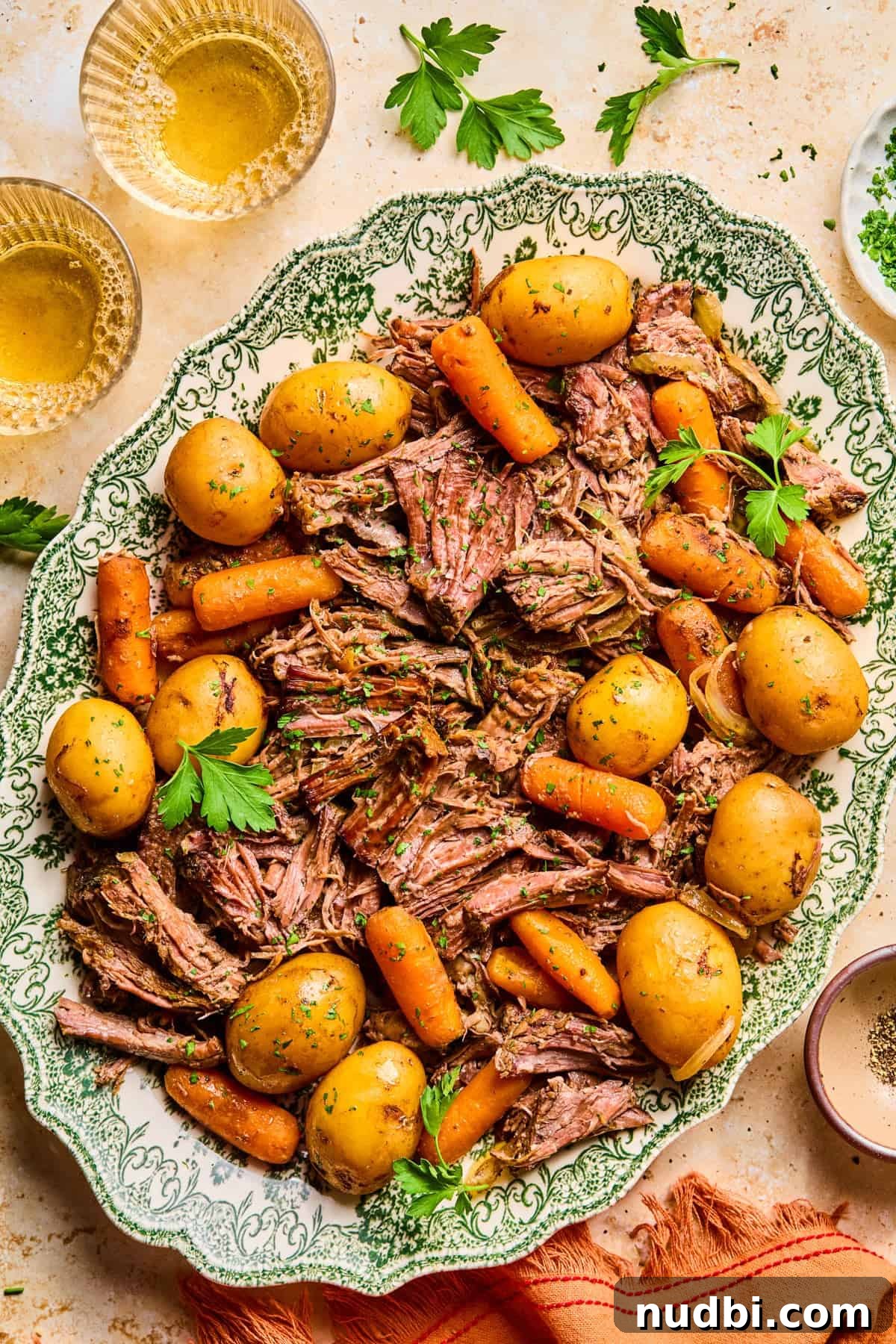Slow-Cooked Chuck Roast Recipe for Tender, Juicy Beef 2 Crockpot chuck roast on serving platter with carrots, onion and petite potatoes and topped with chopped parsley.