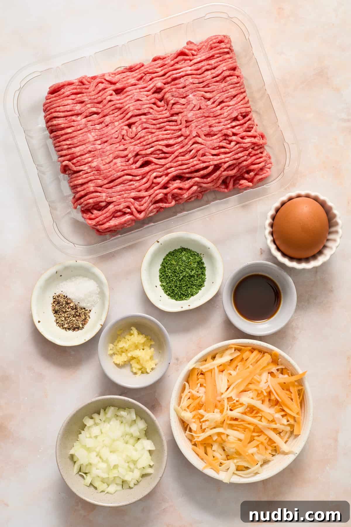 Crispy Air Fryer Hamburgers: Juicy Patties in Minutes 3 Beef, seasoning, egg, cheese, onion and other ingredients prepped for recipe.