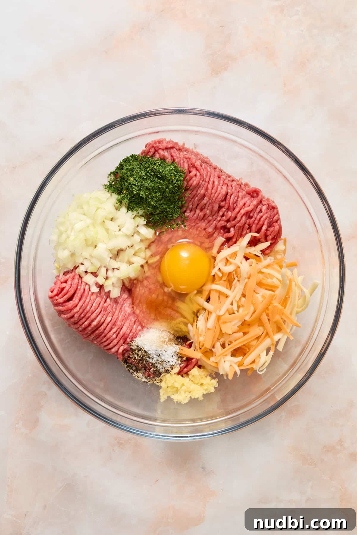 Crispy Air Fryer Hamburgers: Juicy Patties in Minutes 4 Ground beef, egg, cheese, onion, and other ingredients in glass mixing bowl.