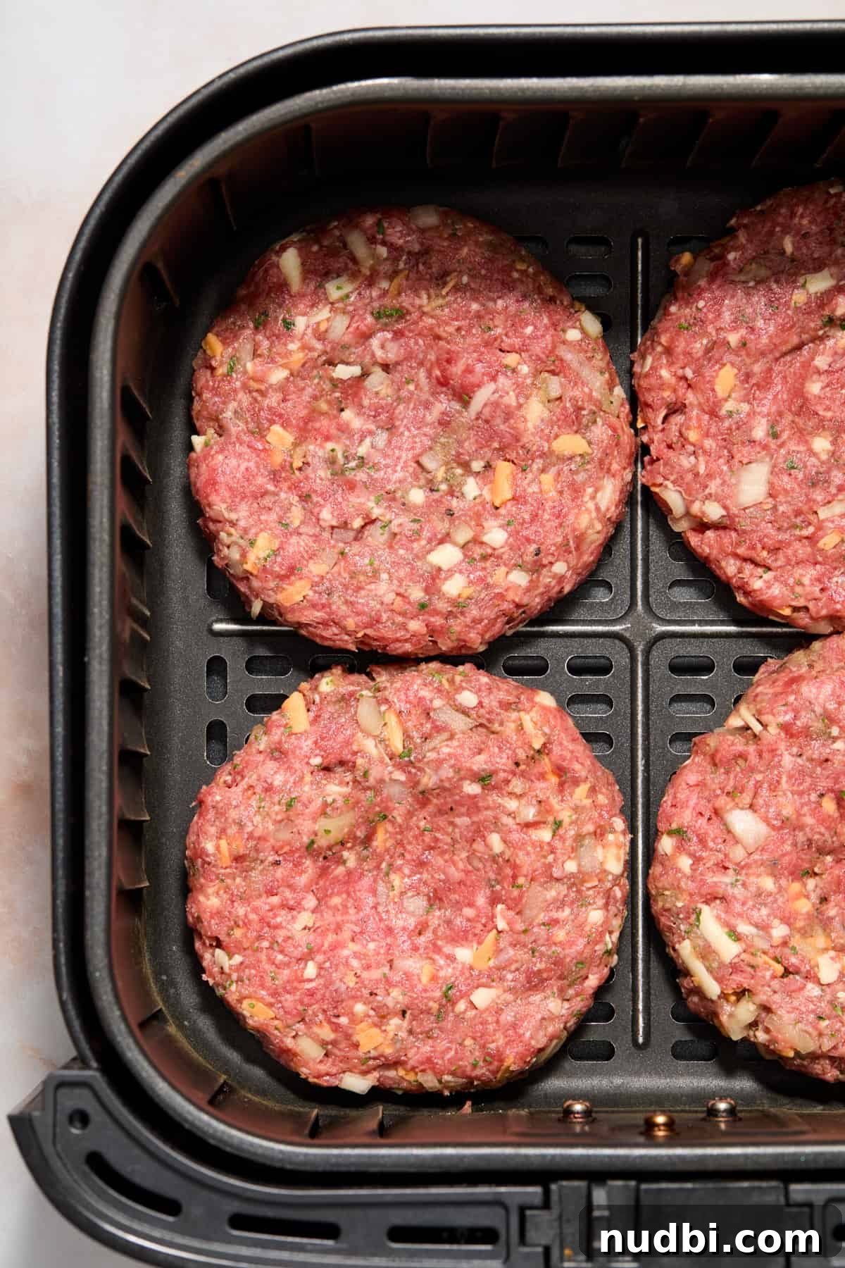 Crispy Air Fryer Hamburgers: Juicy Patties in Minutes 7 Hamburger patties arranged in air fryer before cooking.