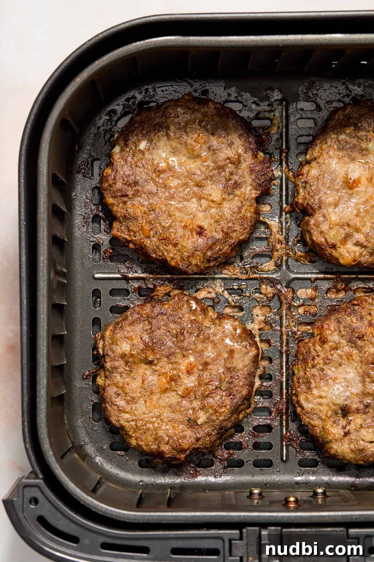Crispy Air Fryer Hamburgers: Juicy Patties in Minutes 8 Air fried hamburger patties in air fryer basket.