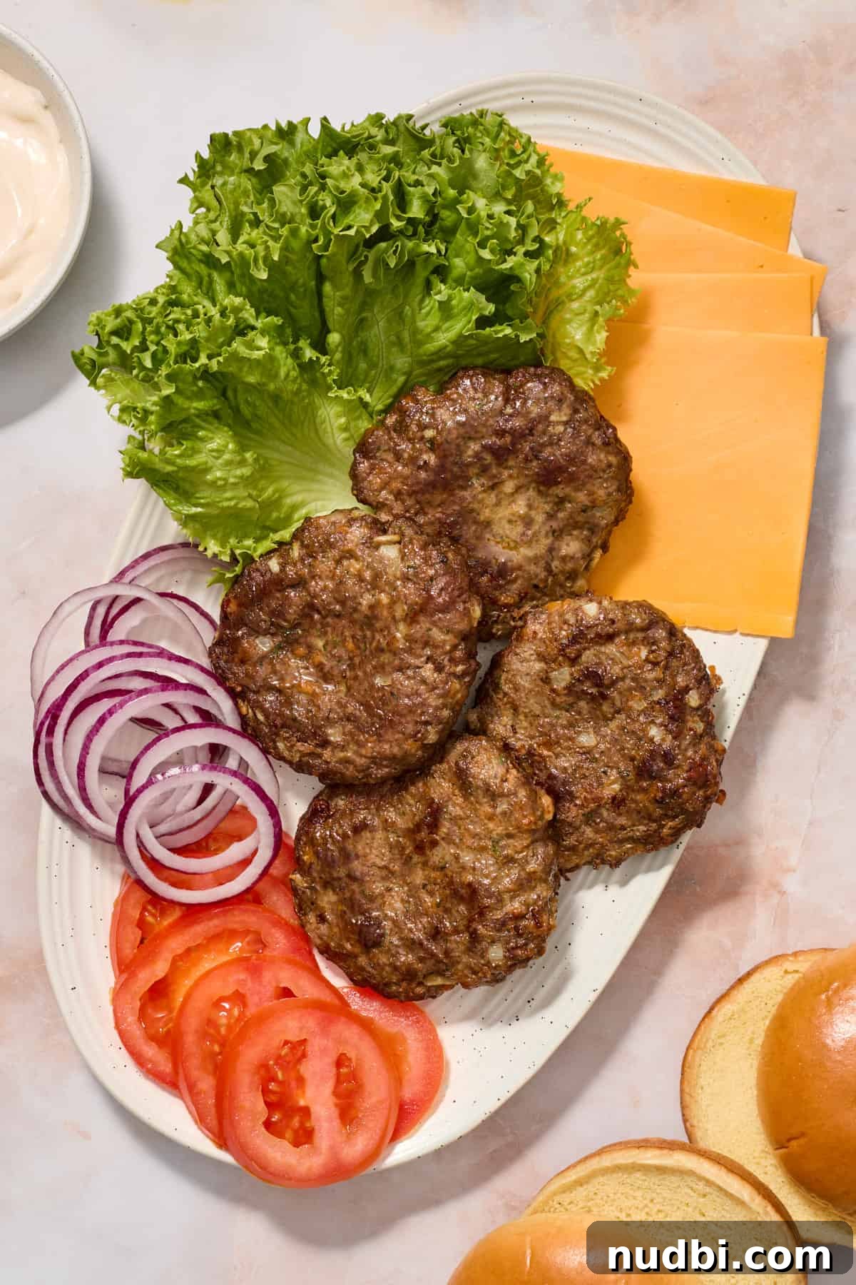 Crispy Air Fryer Hamburgers: Juicy Patties in Minutes 9 Hamburger patties on serving platter with lettuce, tomato, onion and cheese for serving.