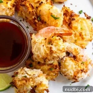 Air Fryer Coconut Shrimp with Honey Sriracha Dipping Sauce 6 Coconut shrimp on white plate with sauce.