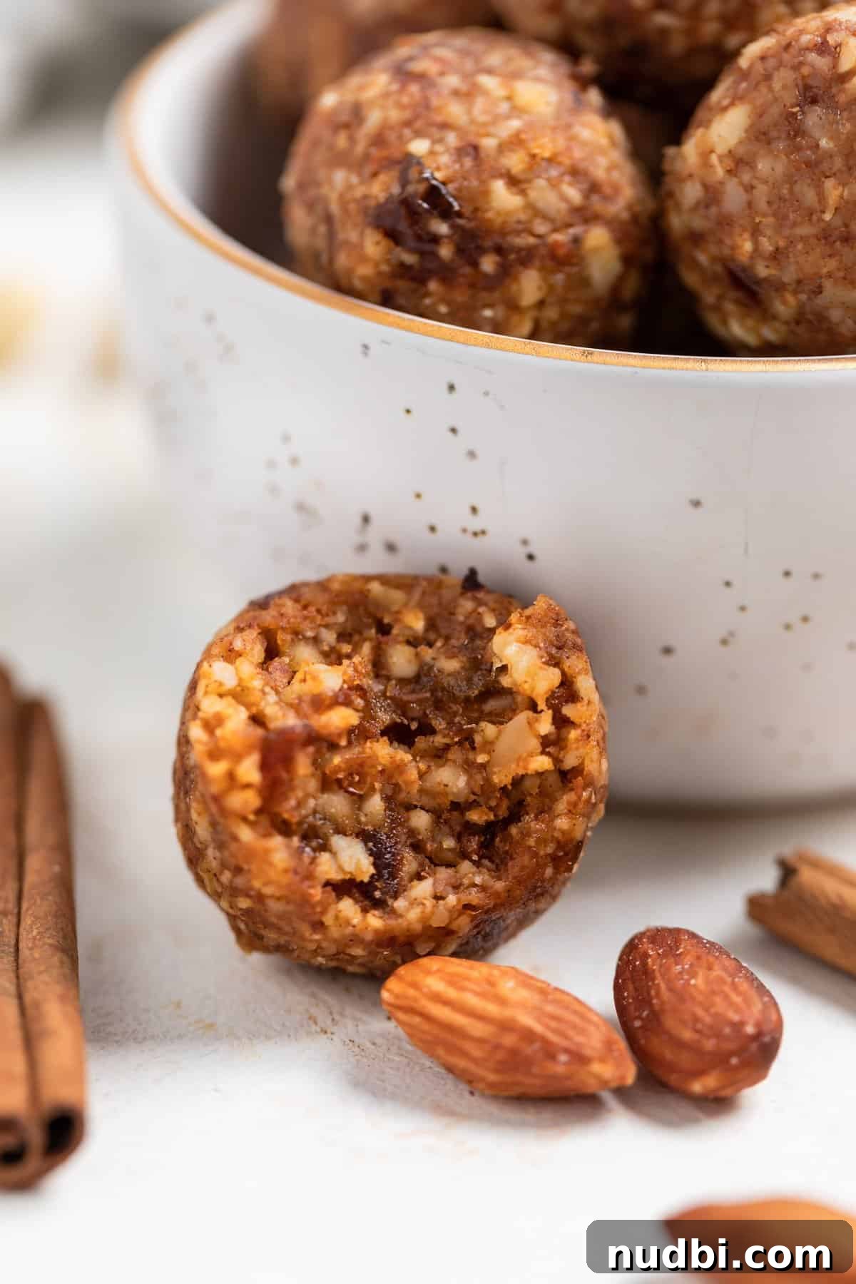 Pumpkin Pie Energy Bites: Fall Snack Recipe with Oats & Dates 3 Pumpkin pie energy bite with bite taken out and set next to a bowl of more bites.