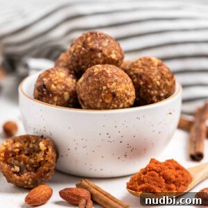 Pumpkin Pie Energy Bites: Fall Snack Recipe with Oats & Dates 5 Pumpkin energy bites in bowl with one energy bite beside it as well as a spoon of pumpkin.