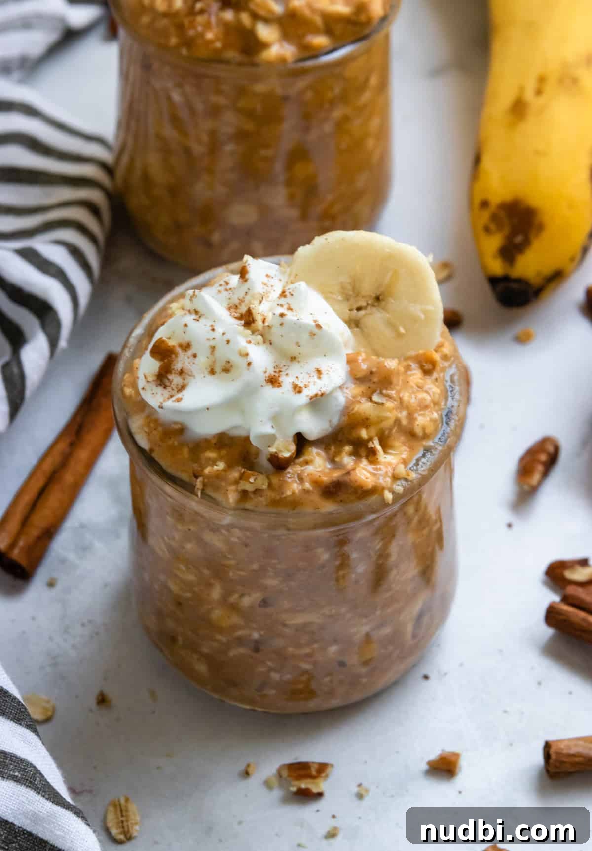 Pumpkin Banana Overnight Oats Recipe for Fall Breakfast 2 Pumpkin banana overnight oats in jars with banana slices and whipped cream.