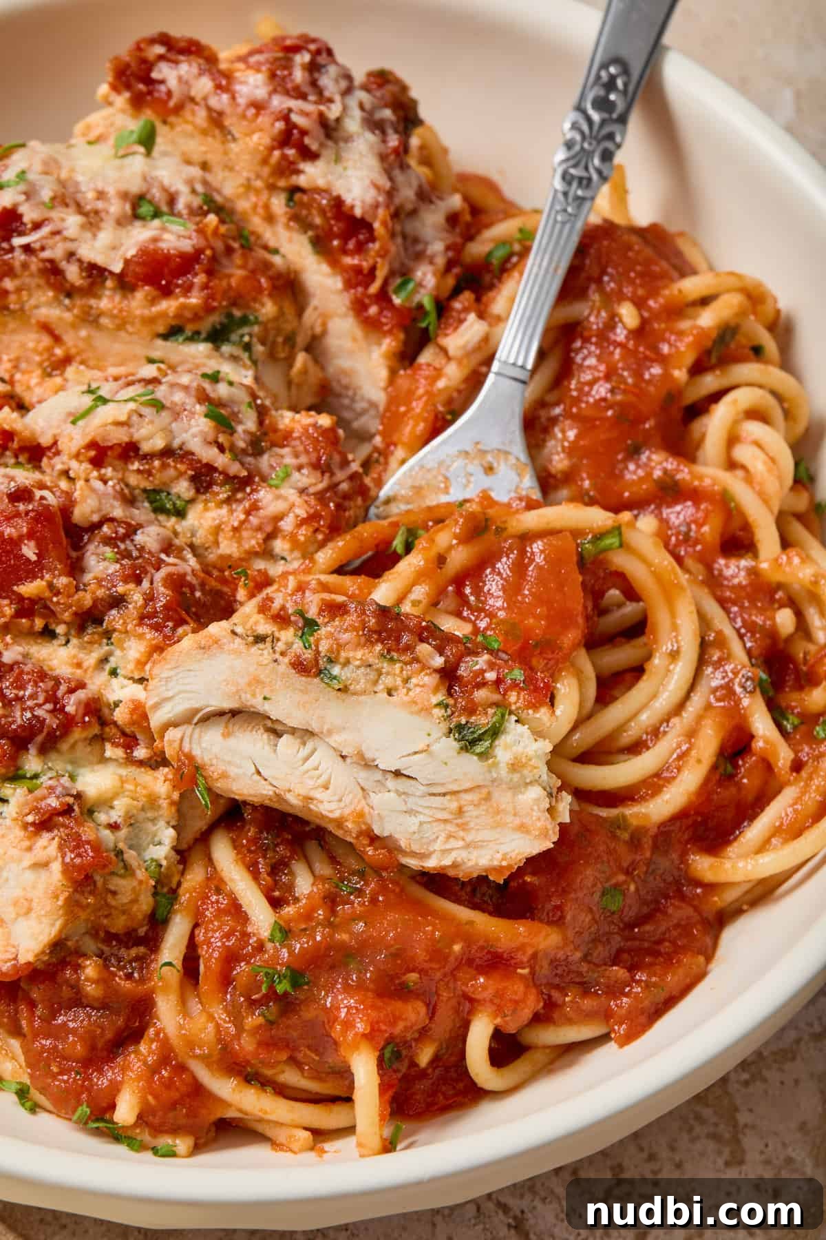 Spinach and Ricotta Stuffed Chicken Breast Recipe 9 Piece of baked spinach ricotta chicken on fork set in bowl of spaghetti.