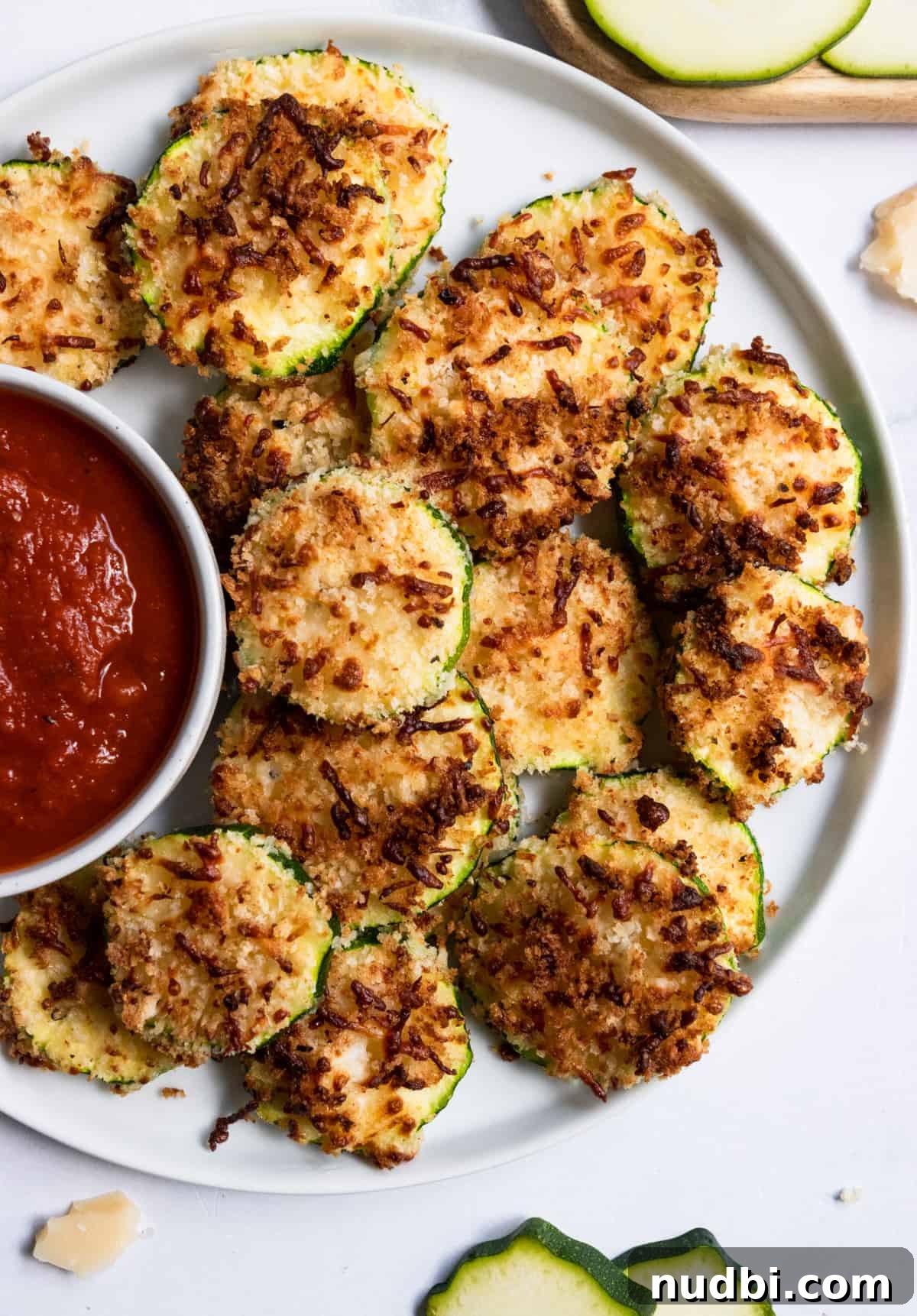 Crispy Air Fryer Zucchini with Three-Cheese Coating 6 Overhead view of crispy zucchini on white plate.
