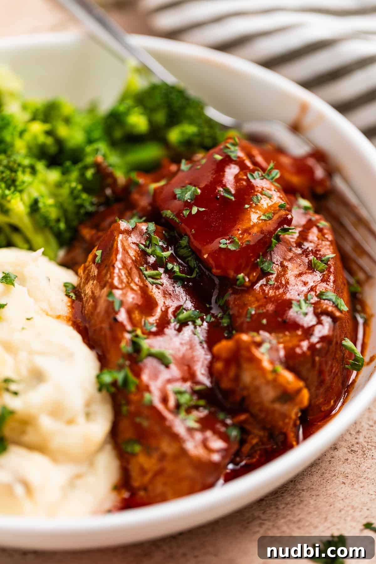 Slow-Cooker Country-Style BBQ Ribs: Tender, Fall-Off-the-Bone Recipe 4 White plate with BBQ sauce covered boneless pork ribs with potatoes and broccoli.