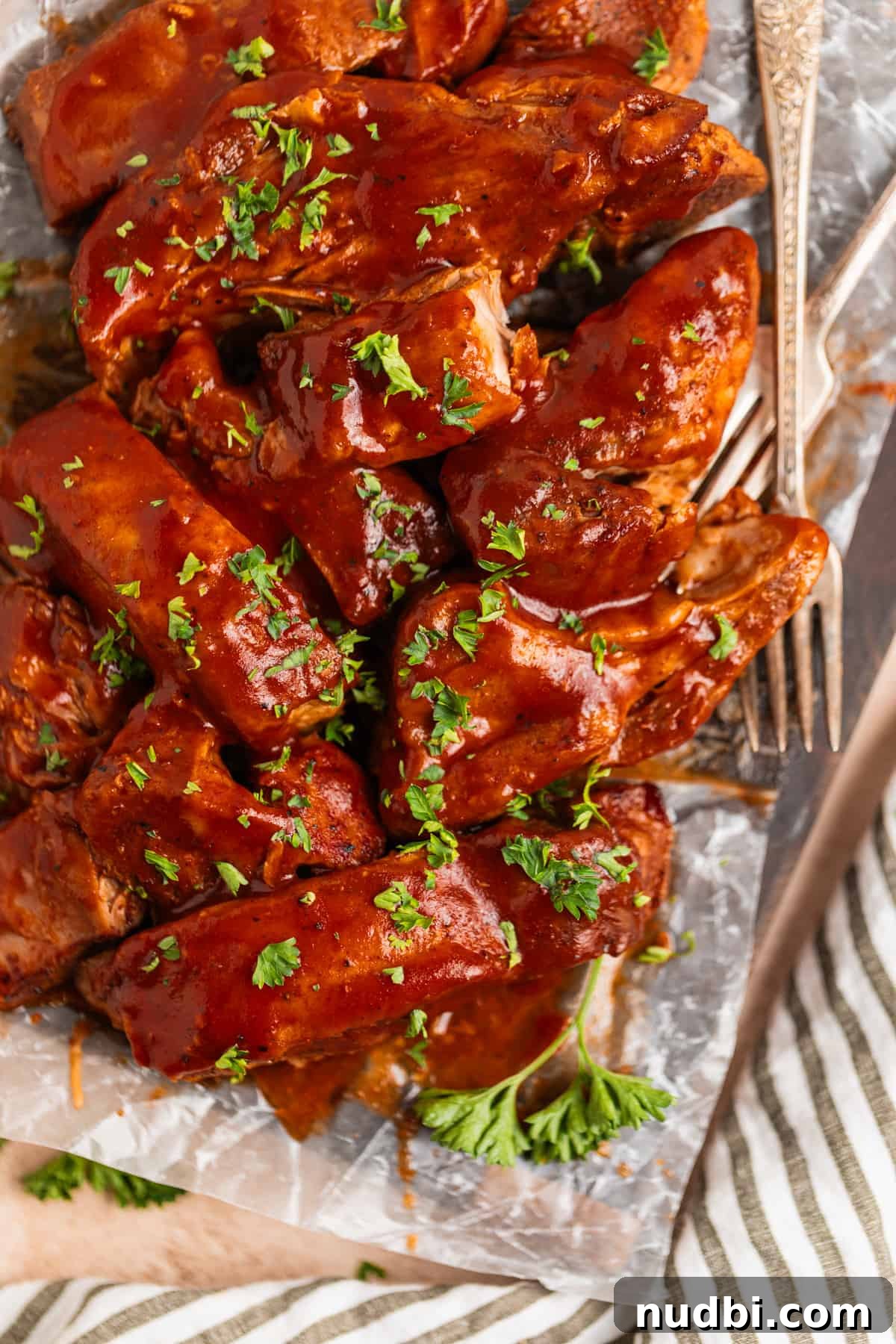 Slow-Cooker Country-Style BBQ Ribs: Tender, Fall-Off-the-Bone Recipe 9 Slow cooker country ribs topped with BBQ sauce and chopped parsley on wood cutting board lined with wax paper.