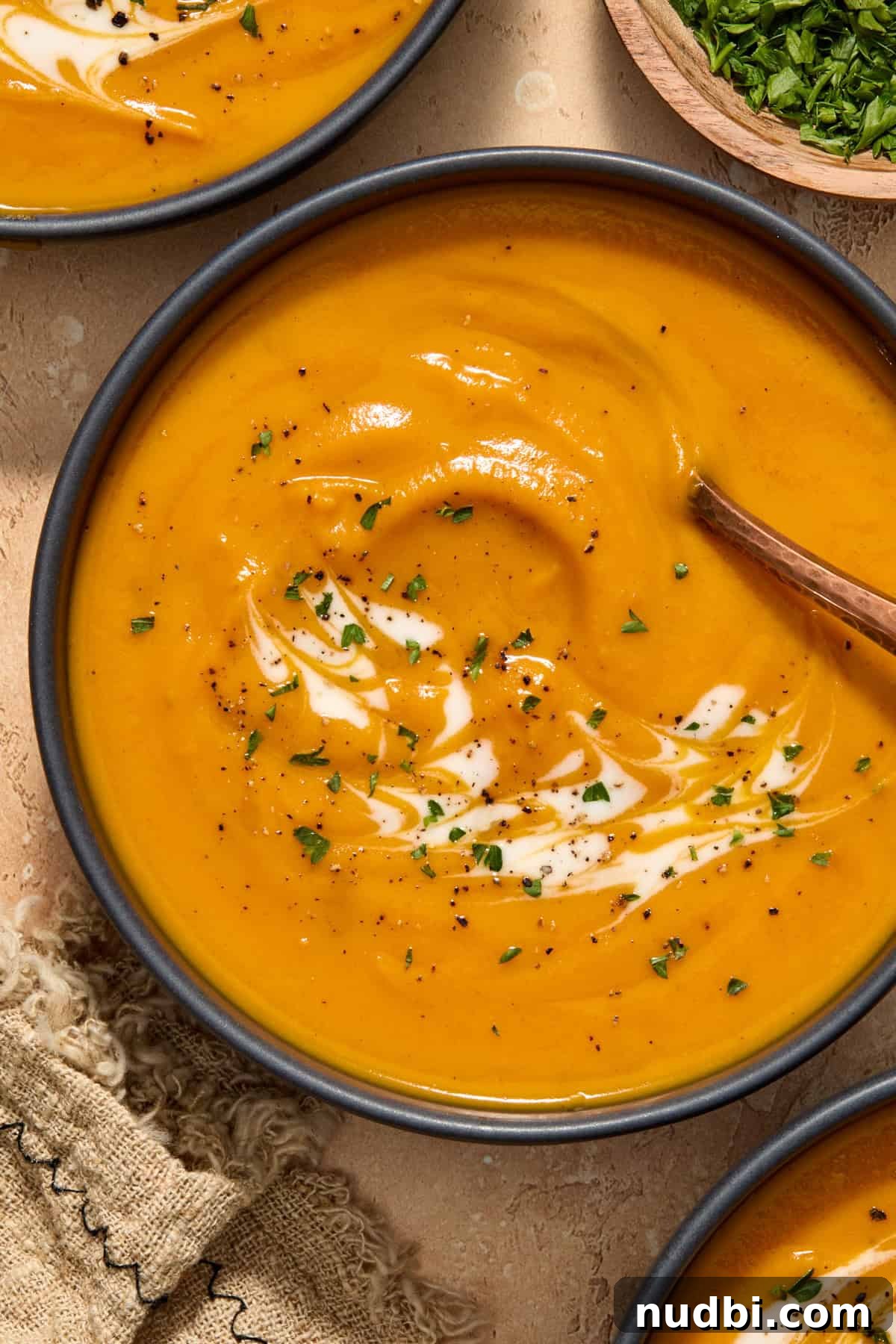 Maple-Roasted Sweet Potato and Carrot Soup Recipe 2 Bowl of carrot and sweet potato soup with cream and herbs swirled over top.