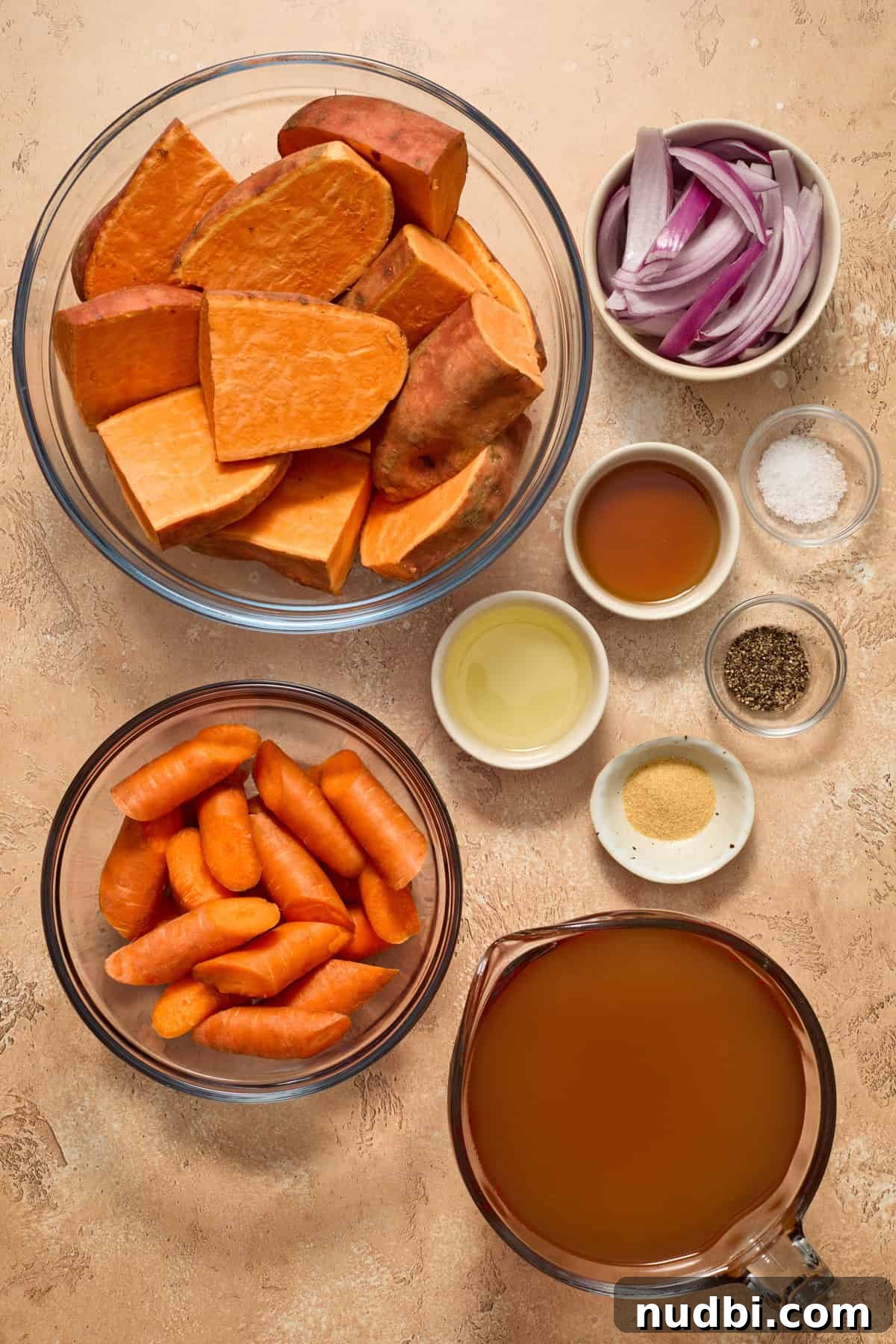 Maple-Roasted Sweet Potato and Carrot Soup Recipe 4 Cut sweet potatoes, onions, carrots, broth and other ingredients needed to make recipe on surface.